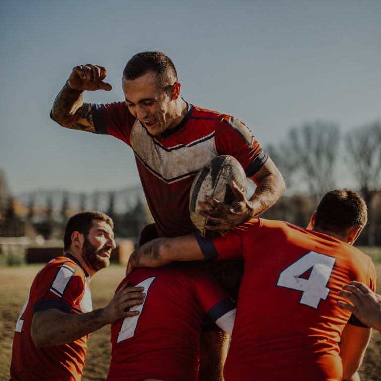 Soccer players celebrating a goal on a field with a stadium in the background